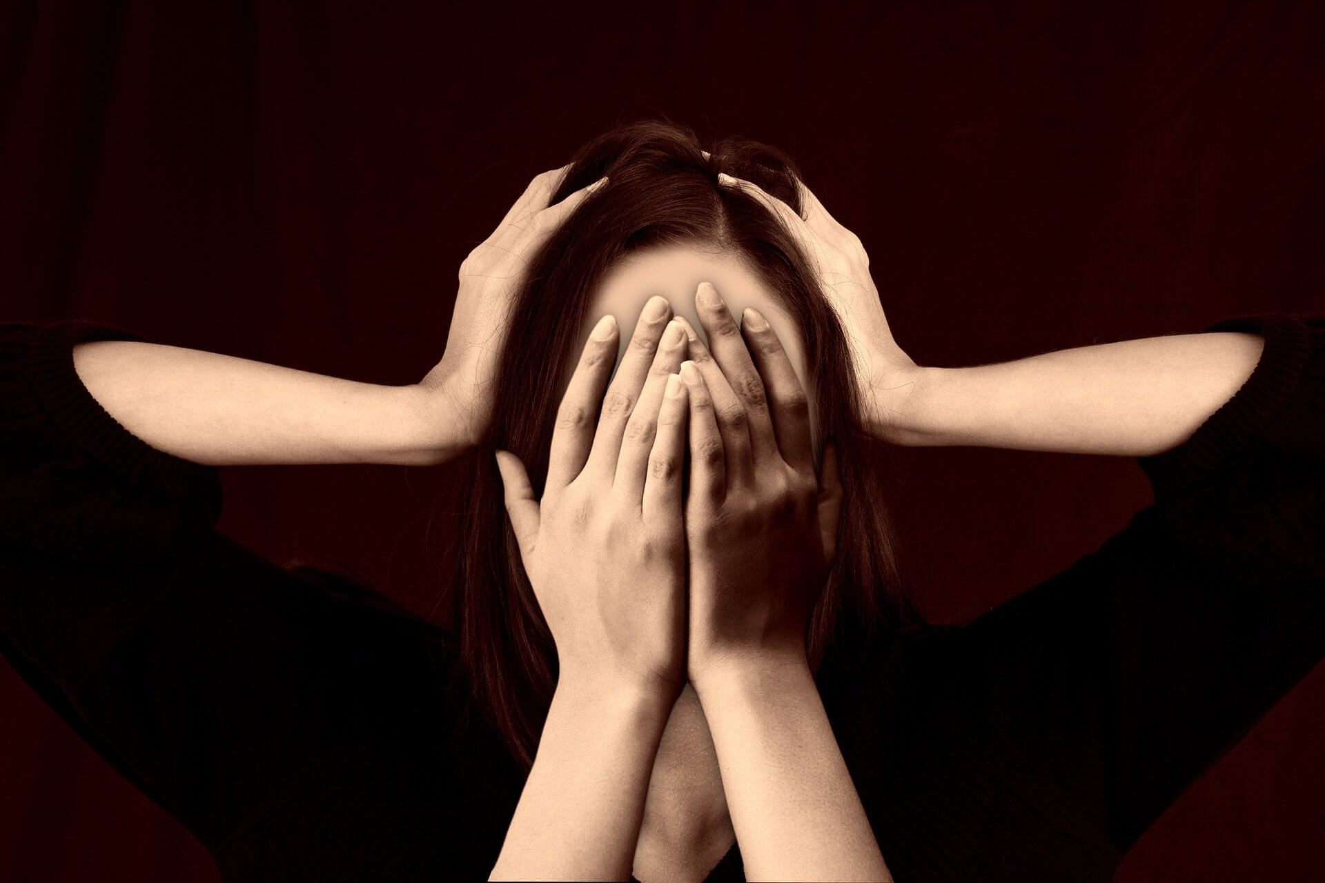 Une femme avec 2 mains sur le visage et 2 mains sur la tête