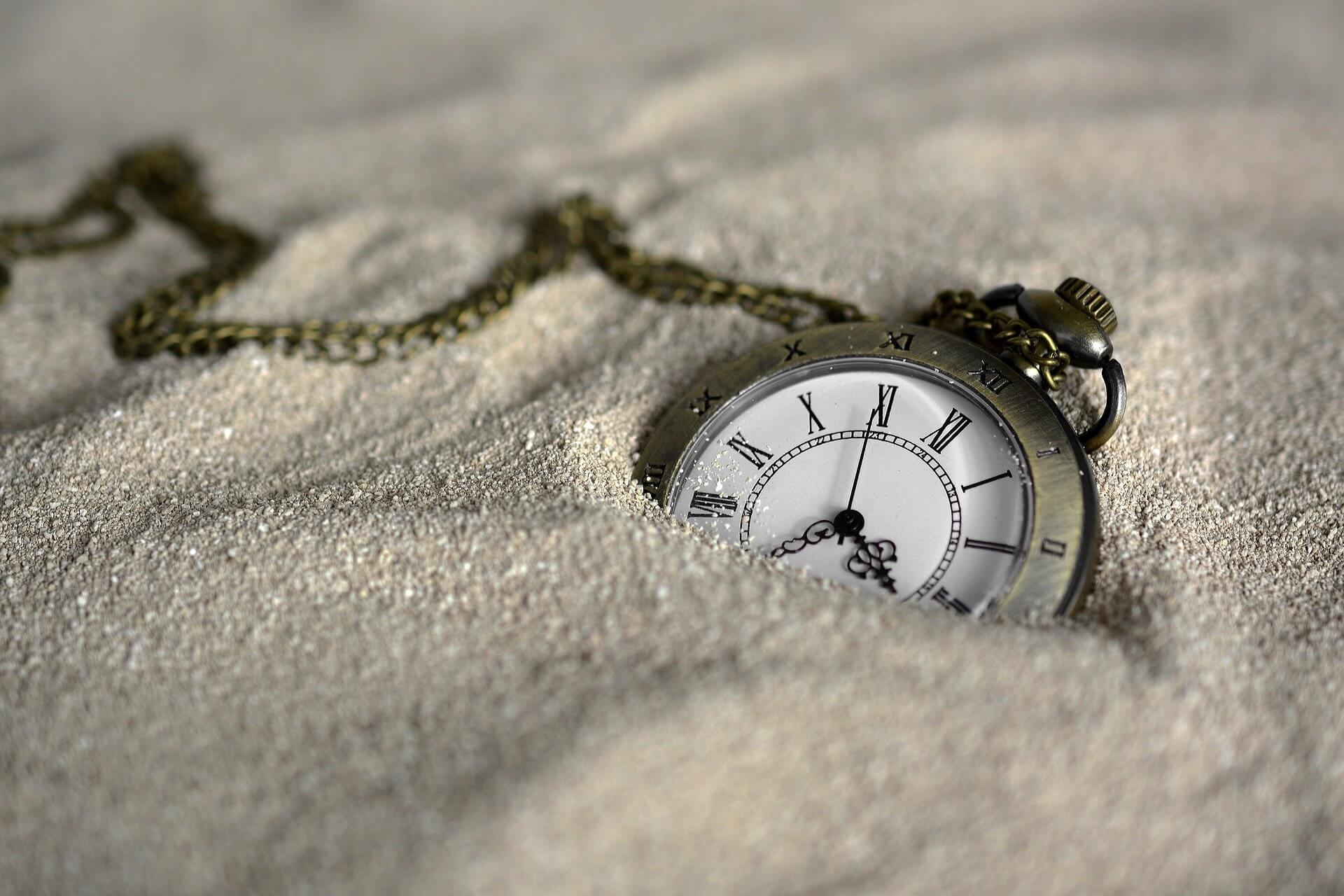 Montre de poche dans du sable, à moitié recouverte