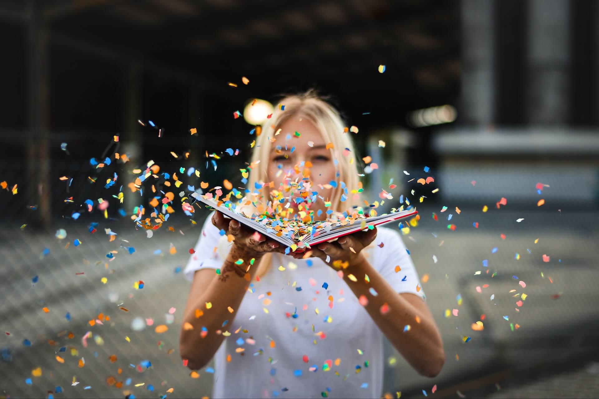 Femme avec livre ouvert sur les mains qu souffle sur des confettis